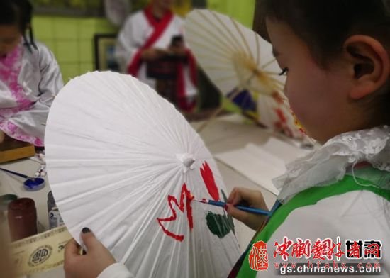 小朋友在纸伞上作画。刘玉桃 摄