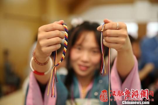 图为桂林汉服爱好者现场展示编织五彩绳。