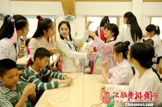 图为桂林汉服爱好者现场教学编织五彩绳。